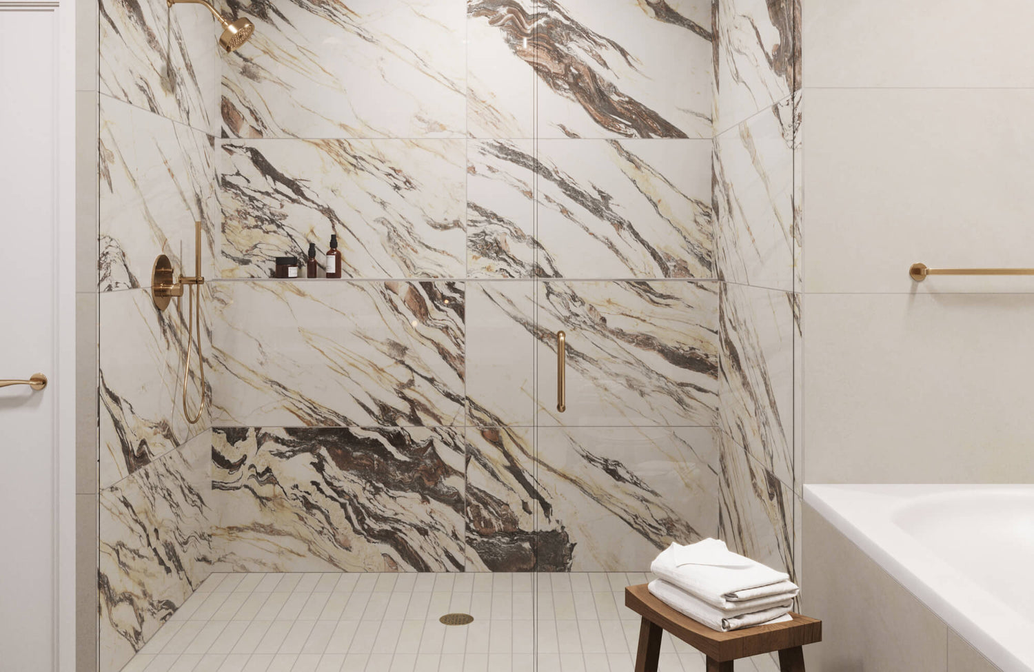 Bathroom shower clad in white and beige marble look tiles with dramatic brown veining, paired with gold-toned hardware.