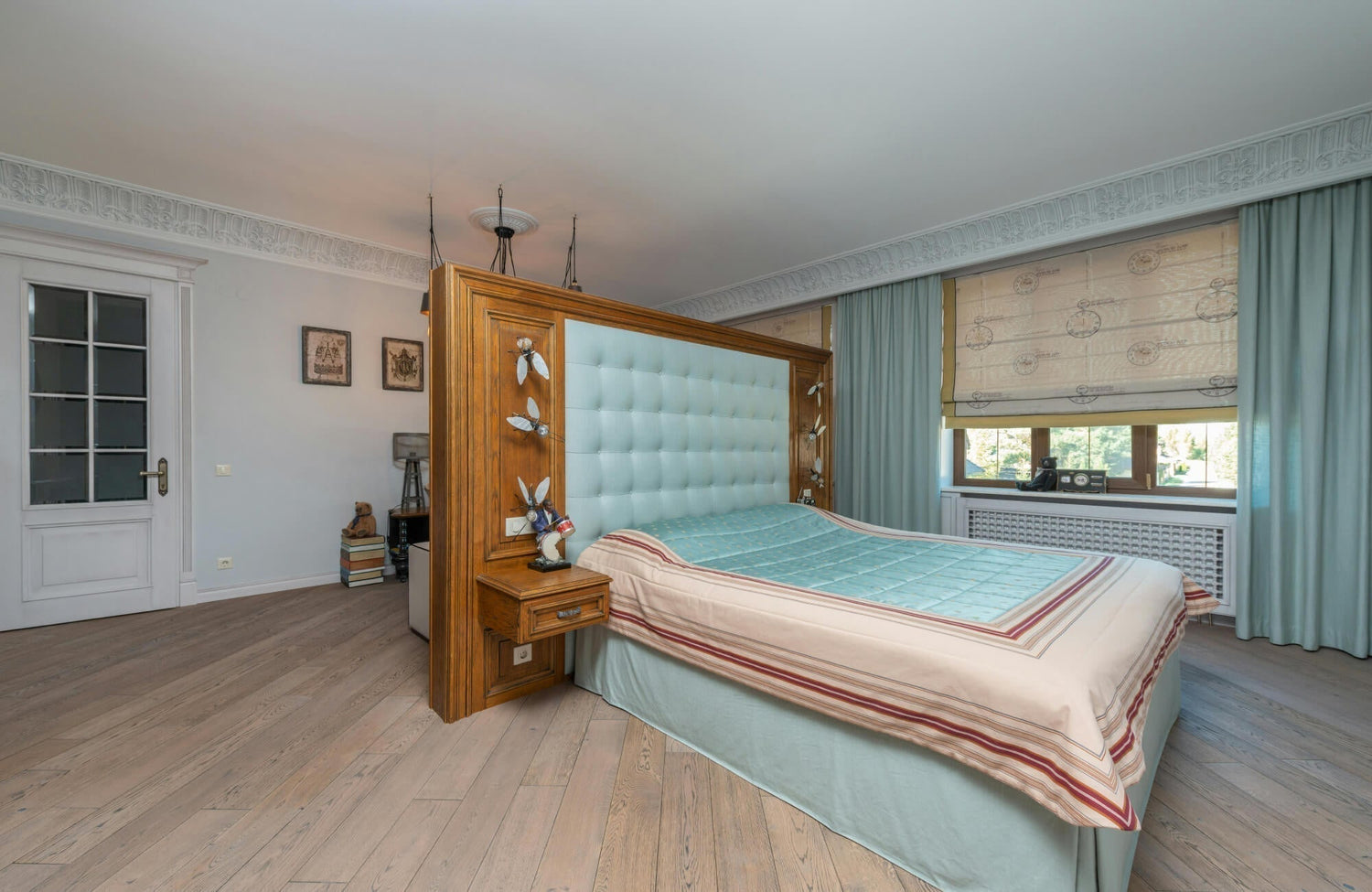 Elegant bedroom featuring a tufted aqua headboard, pastel bedding, soft blue curtains, and light oak vinyl flooring.