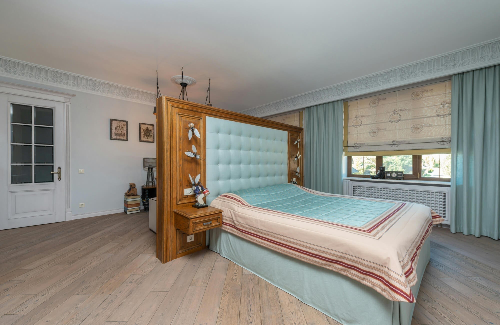 Elegant bedroom featuring a tufted aqua headboard, pastel bedding, soft blue curtains, and light oak vinyl flooring.