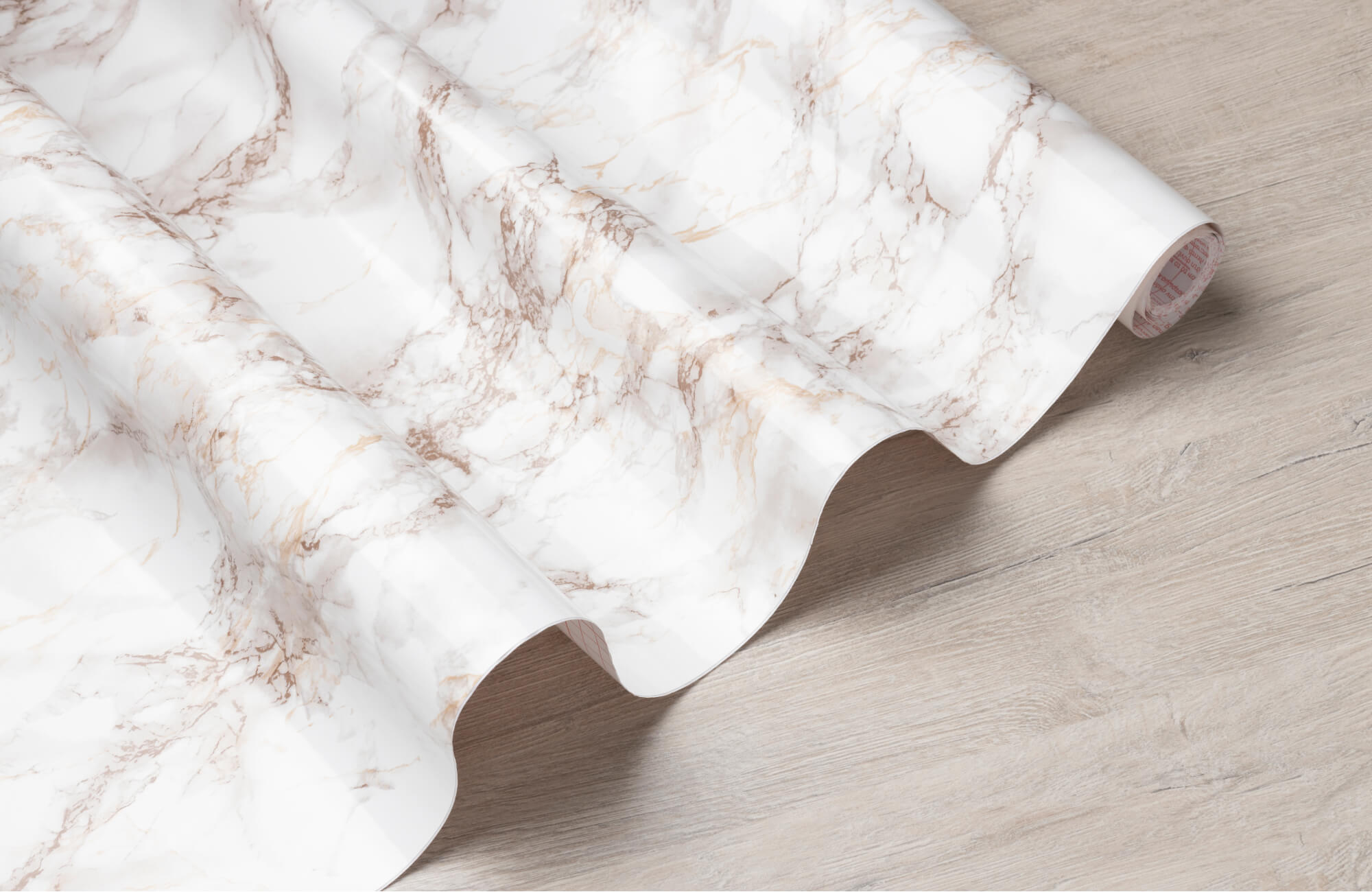 Marble-patterned vinyl sheet rolled out on a wood-look floor, highlighting texture and surface detail.