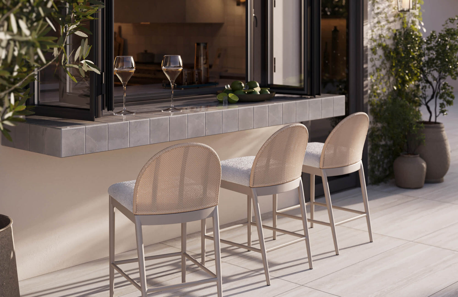 Soft-textured counter stools paired with a tiled pass-through counter, forming a casual outdoor entertaining area with seamless indoor-outdoor flow.
