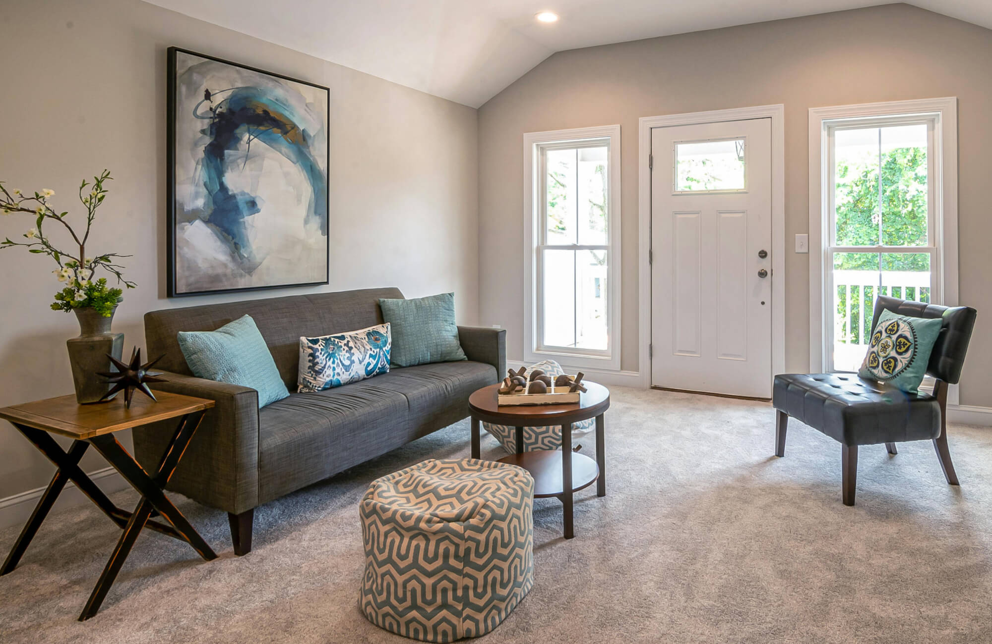 Abstract blue wall art above a gray sofa echoes the blue tones in the pillows, creating a subtle color connection in the living room.