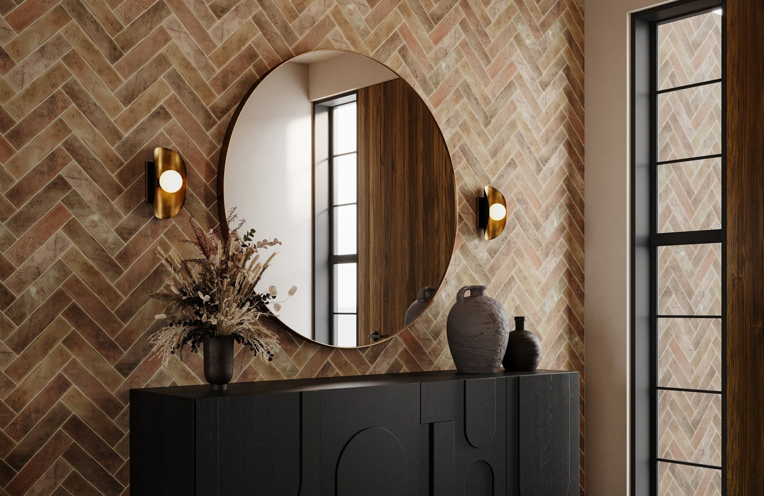 A large circular mirror sits above a black console, surrounded by rustic herringbone tiles and accented by curved brass sconces that cast a soft, warm glow.