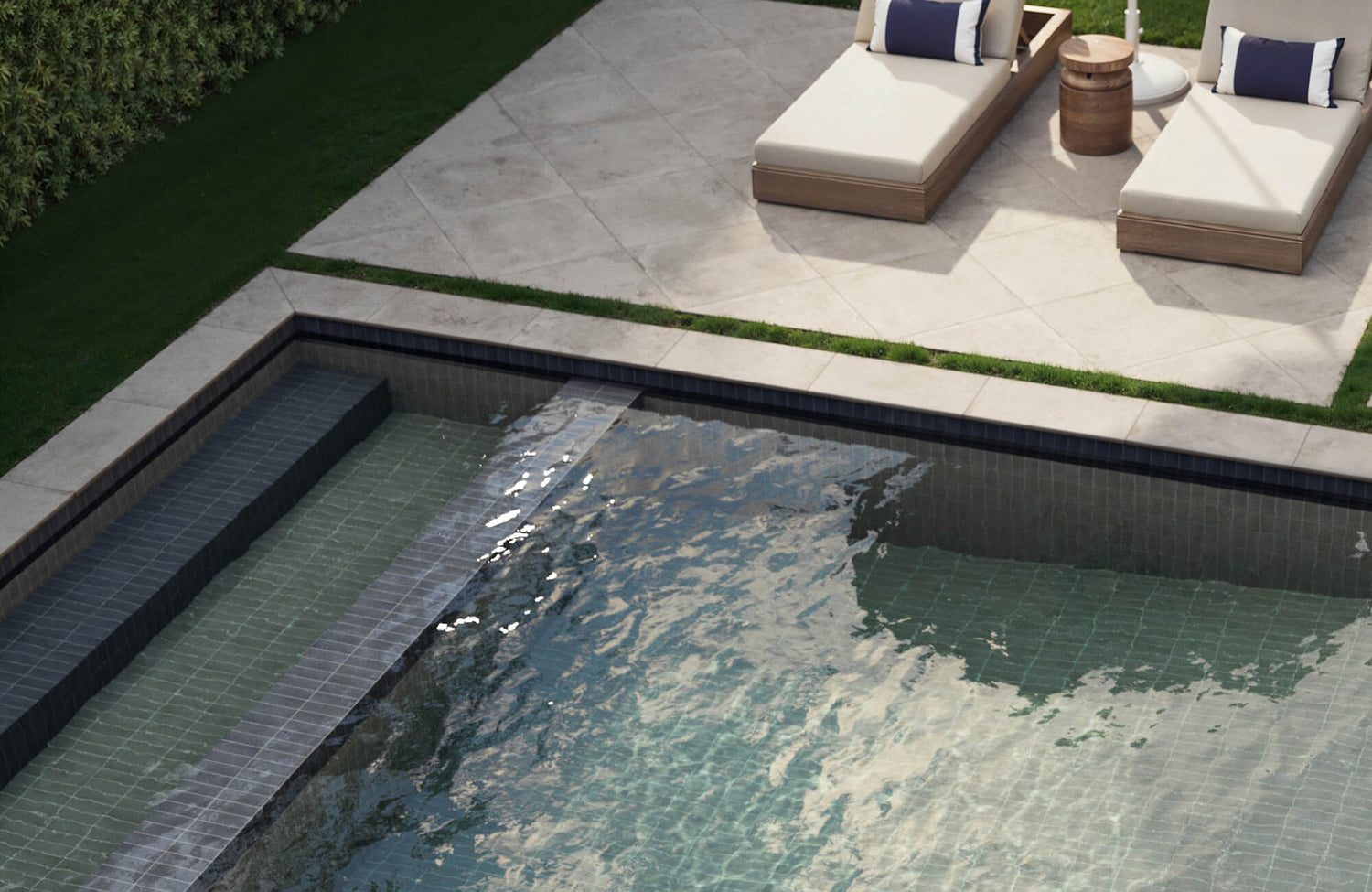 Elegant poolside setting with creamy diamond-set patio tiles and sleek, dark mosaic pool tiles creating modern contrast.