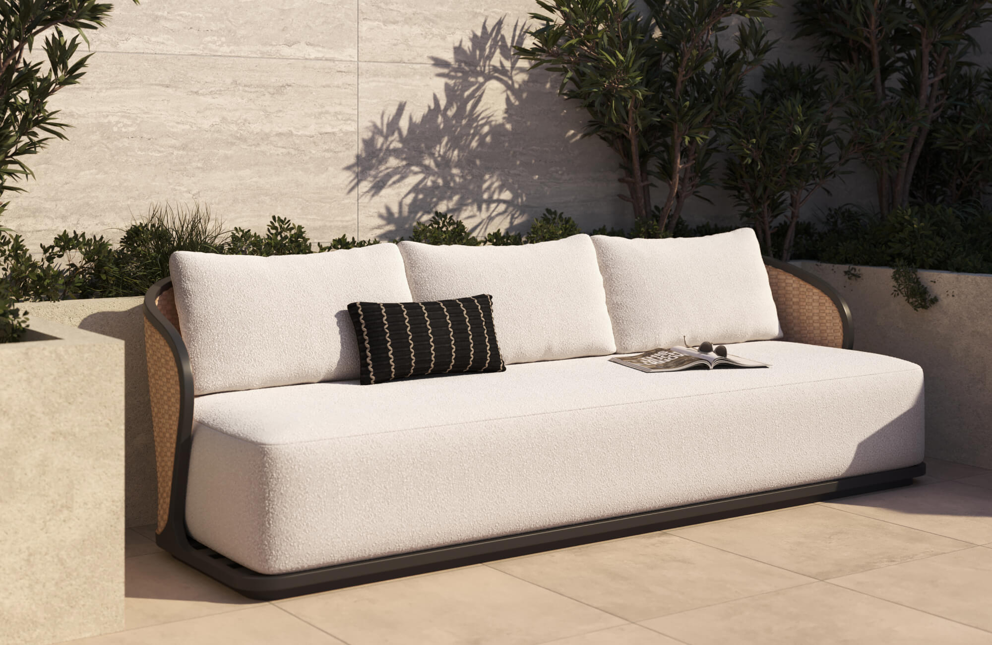 Curved outdoor daybed with textured white cushions beside a pool, styled on a light beige stone patio with tropical greenery and soft afternoon sunlight.