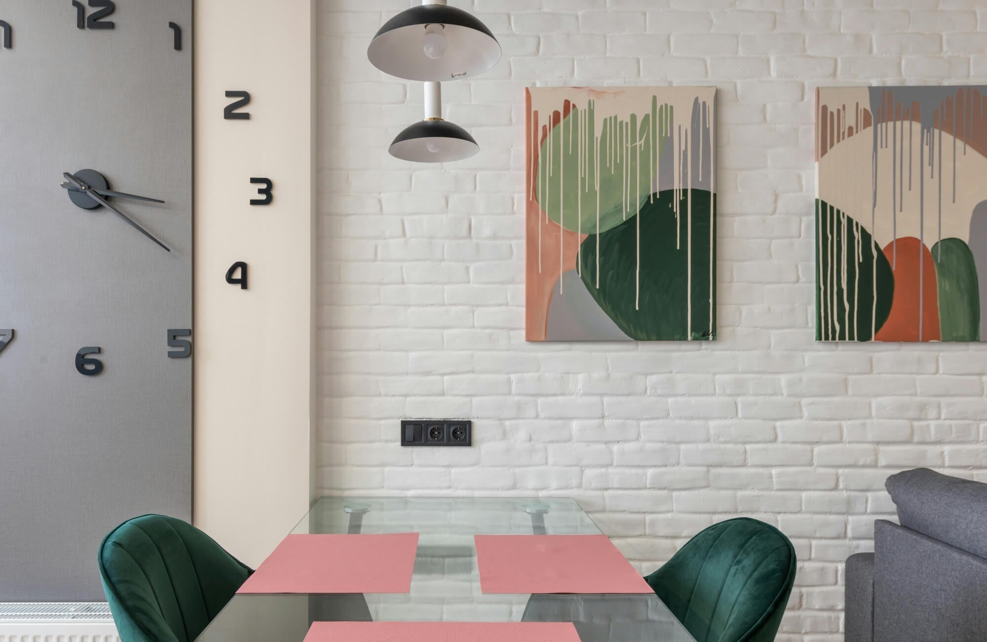 Creative and timeless wall art featuring two abstract canvas paintings with layered green, terracotta, and neutral tones, styled against a white brick wall above a glass dining table to bring modern elegance and artistic character to the space.
