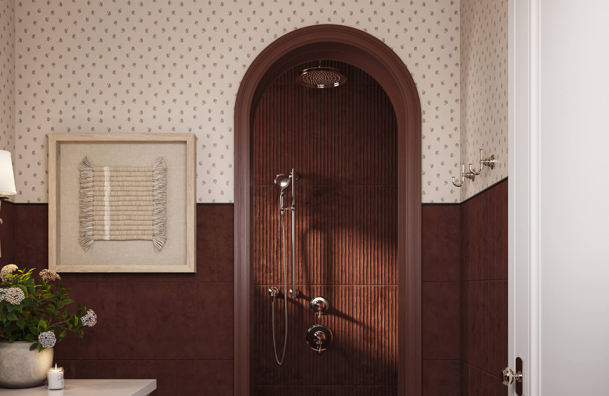 Luxury bathroom with patterned wallpaper, arched shower niche, dark tiles, framed wall art, and brass fixtures creating a warm, elegant design.