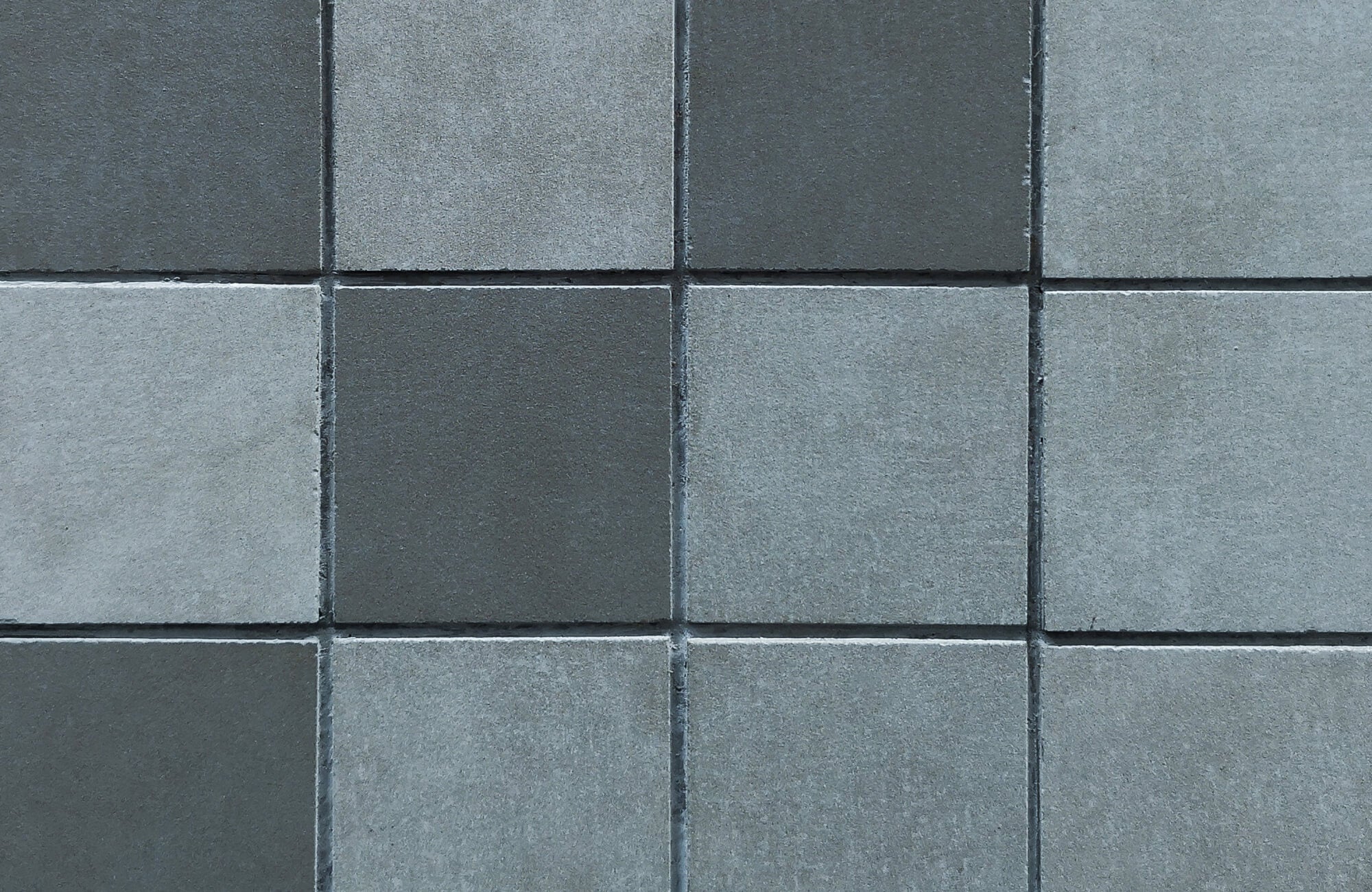 Close-up of gray cementitious tiles arranged in a checkerboard pattern, showcasing their smooth matte texture.