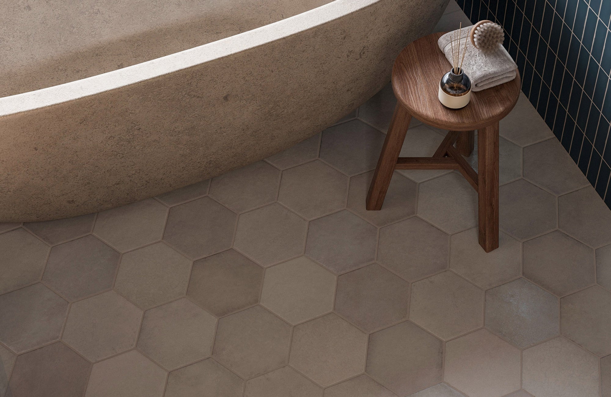 Bathroom floor with large beige hex tiles complementing a stone bathtub and wooden stool for a warm, natural look.