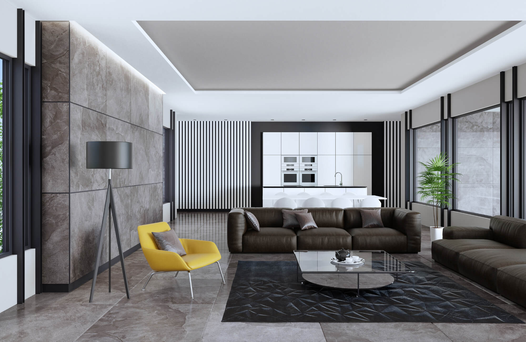 Modern open-plan living room with cement-look tile flooring, dark sofas, a yellow accent chair, and a sleek white kitchen backdrop.