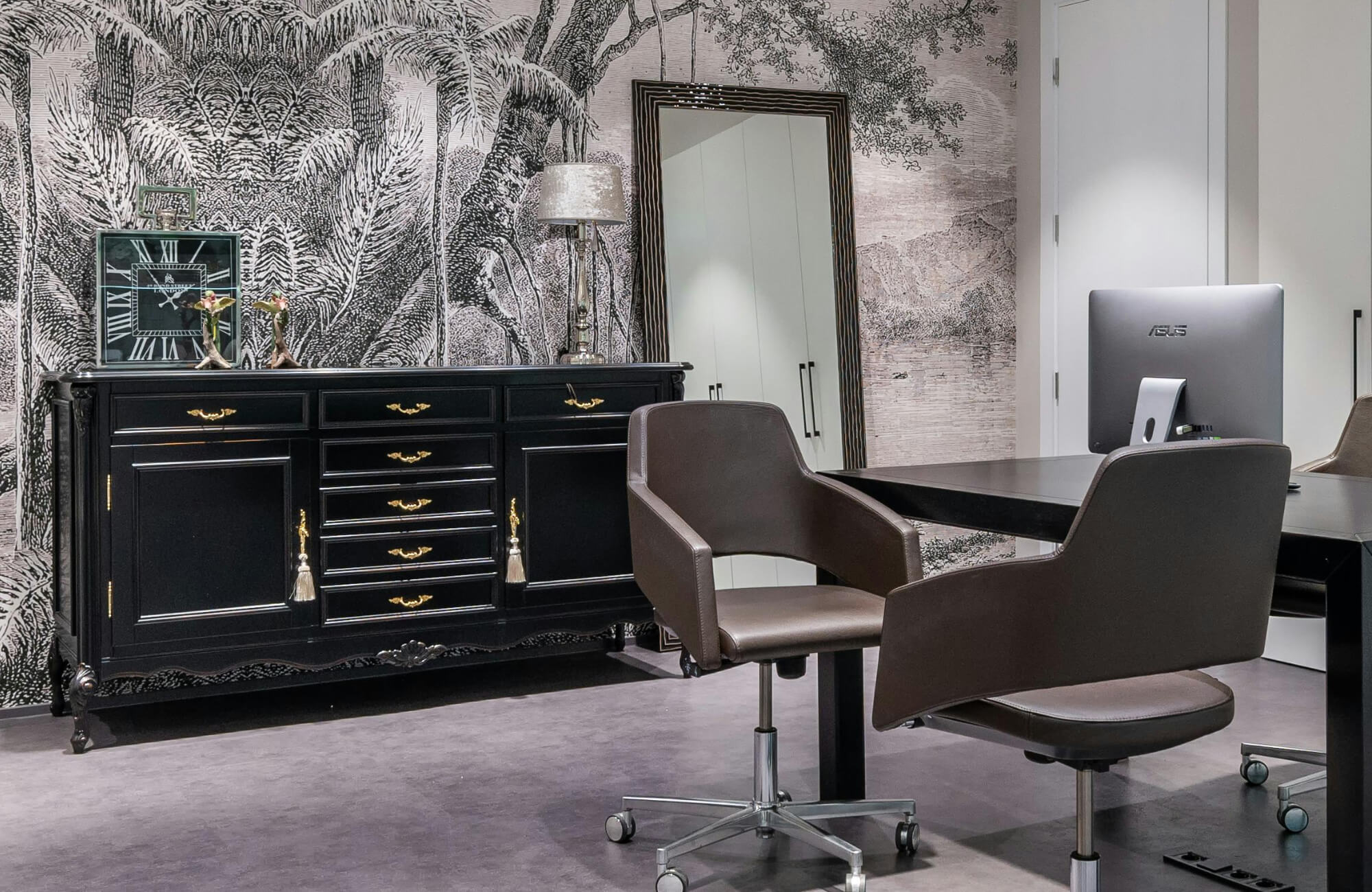 Chic office space with a vintage black sideboard, botanical mural wallpaper, and a long, modern-framed mirror adding depth.