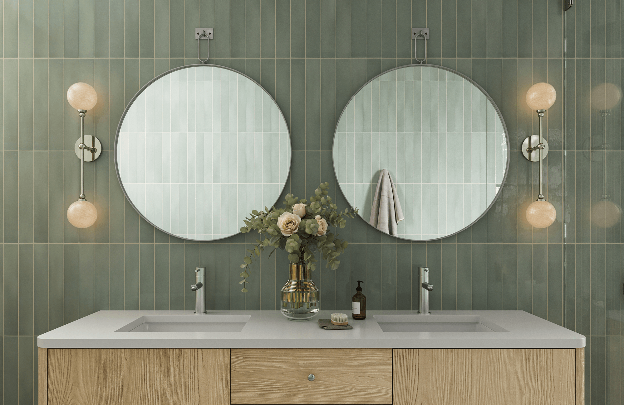 Sleek sage green vertical subway tiles form a serene bathroom backdrop with twin round mirrors, wood vanity, and modern sconces.