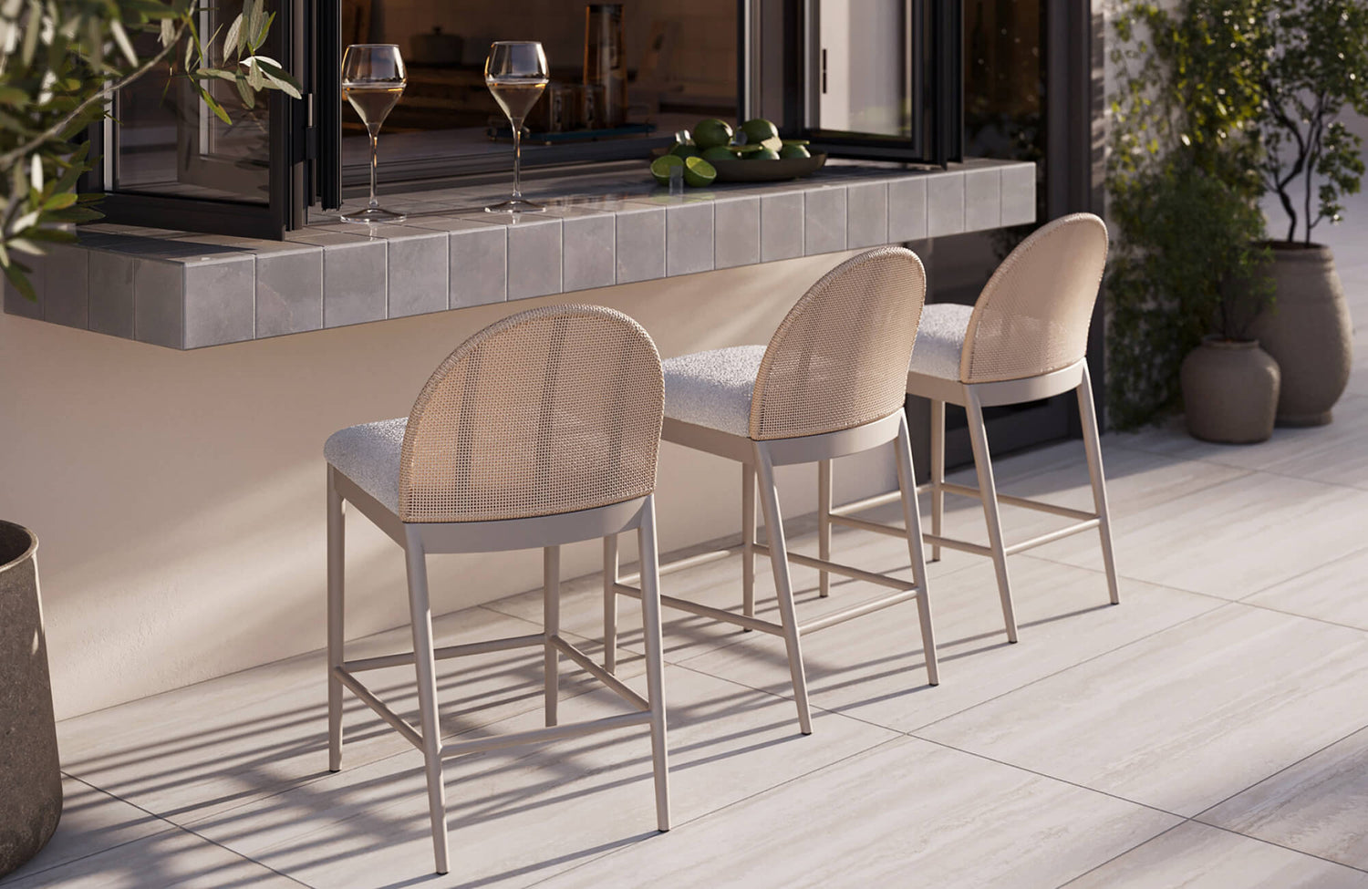 Outdoor counter stools with woven backs and cushioned seats arranged along a tiled bar for relaxed open-air dining