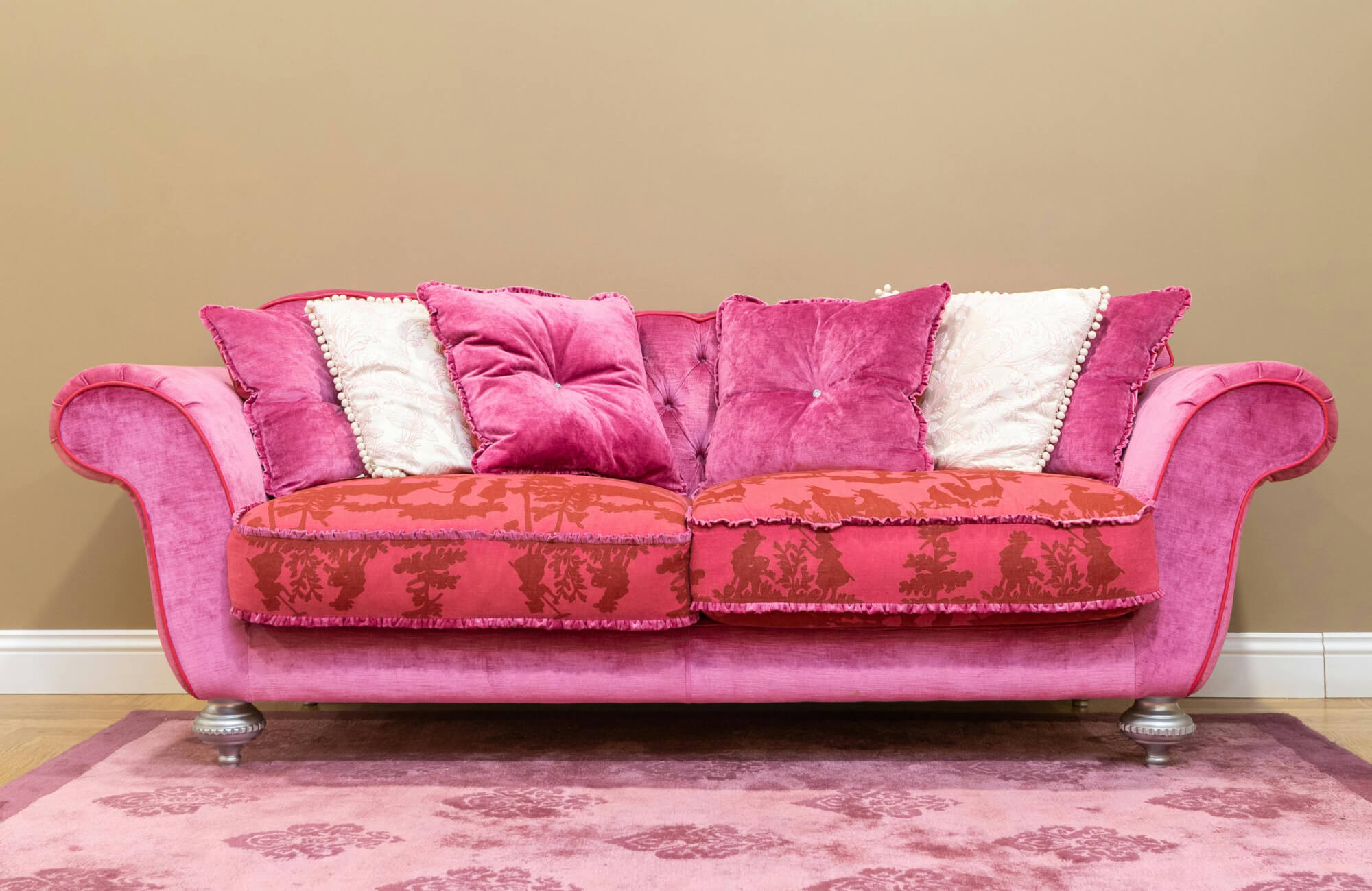 Pink velvet sofa with matching patterned rug and neutral walls creating a bold yet elegant living room design.