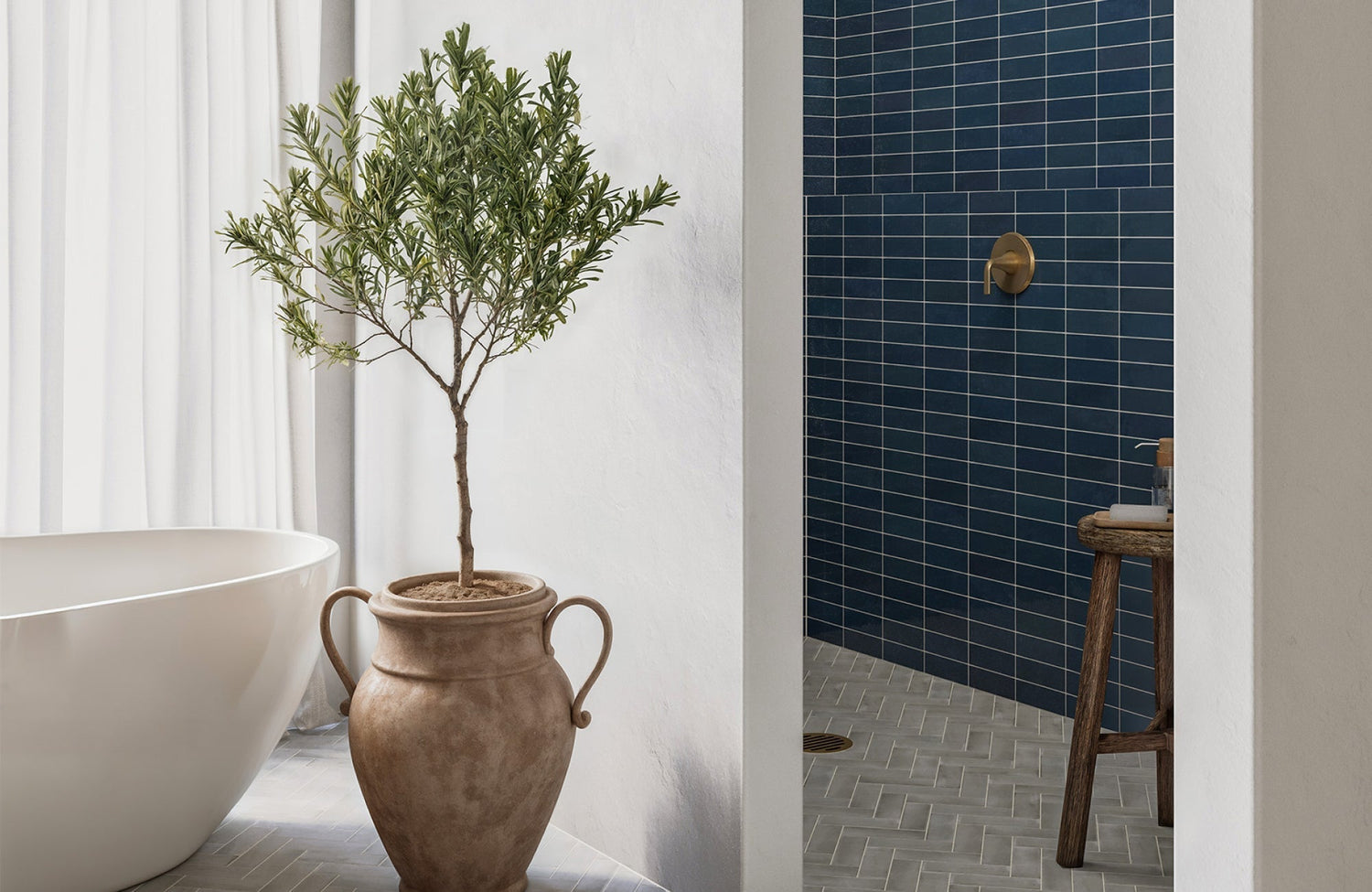 Dark blue shower tiles paired with neutral-toned herringbone flooring and natural terracotta decor for a warm, earthy contrast.