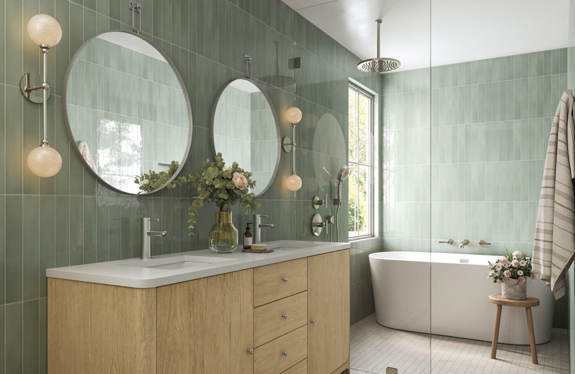 Twin globe wall sconces mounted beside round mirrors in a sage green tile bathroom with a double vanity.