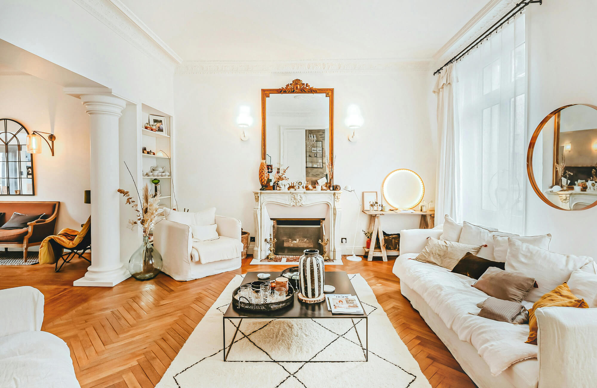 Light-filled classic living room with elegant molding, warm wood floors, and softly layered neutral pillows.