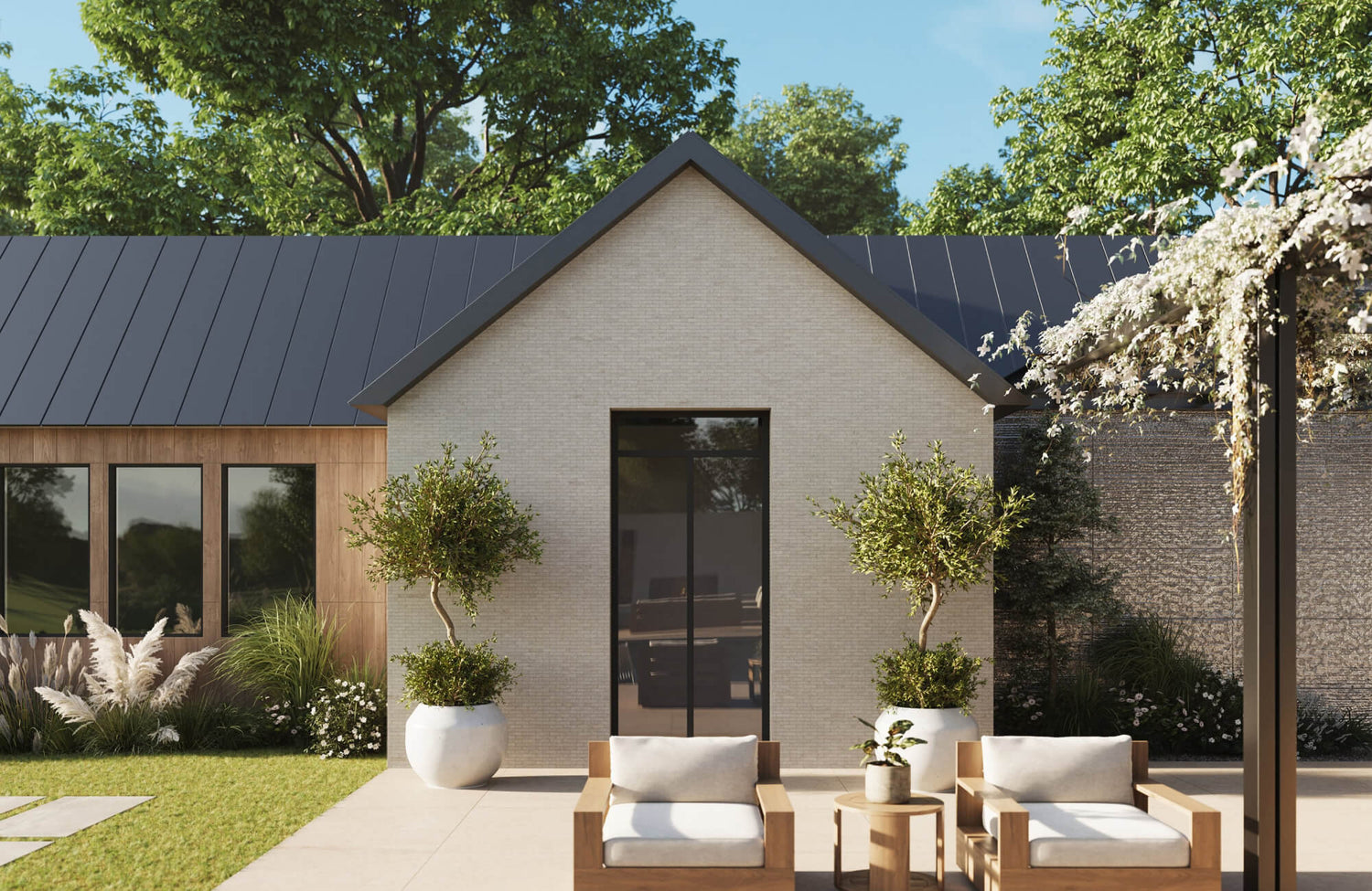 Outdoor lounge patio with wood-framed chairs, cream cushions, and a small round side table, creating a warm, natural seating area beside a garden and modern exterior.