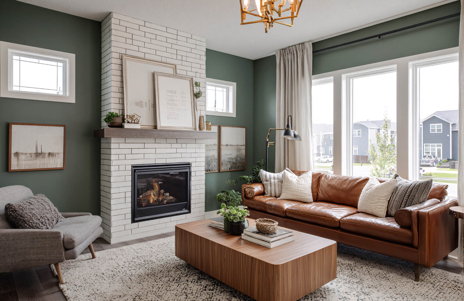 Modern living room with a white porcelain tile fireplace surround, warm wood mantel, and green walls creating a balanced, cozy focal point.