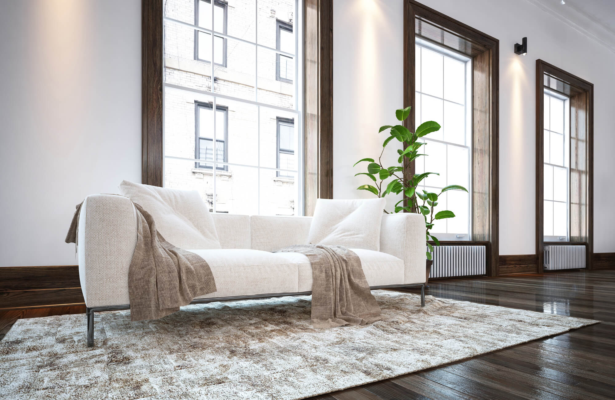 Bright living room with wood looking tile flooring transitioning to a soft area rug beneath a modern sofa and large windows.