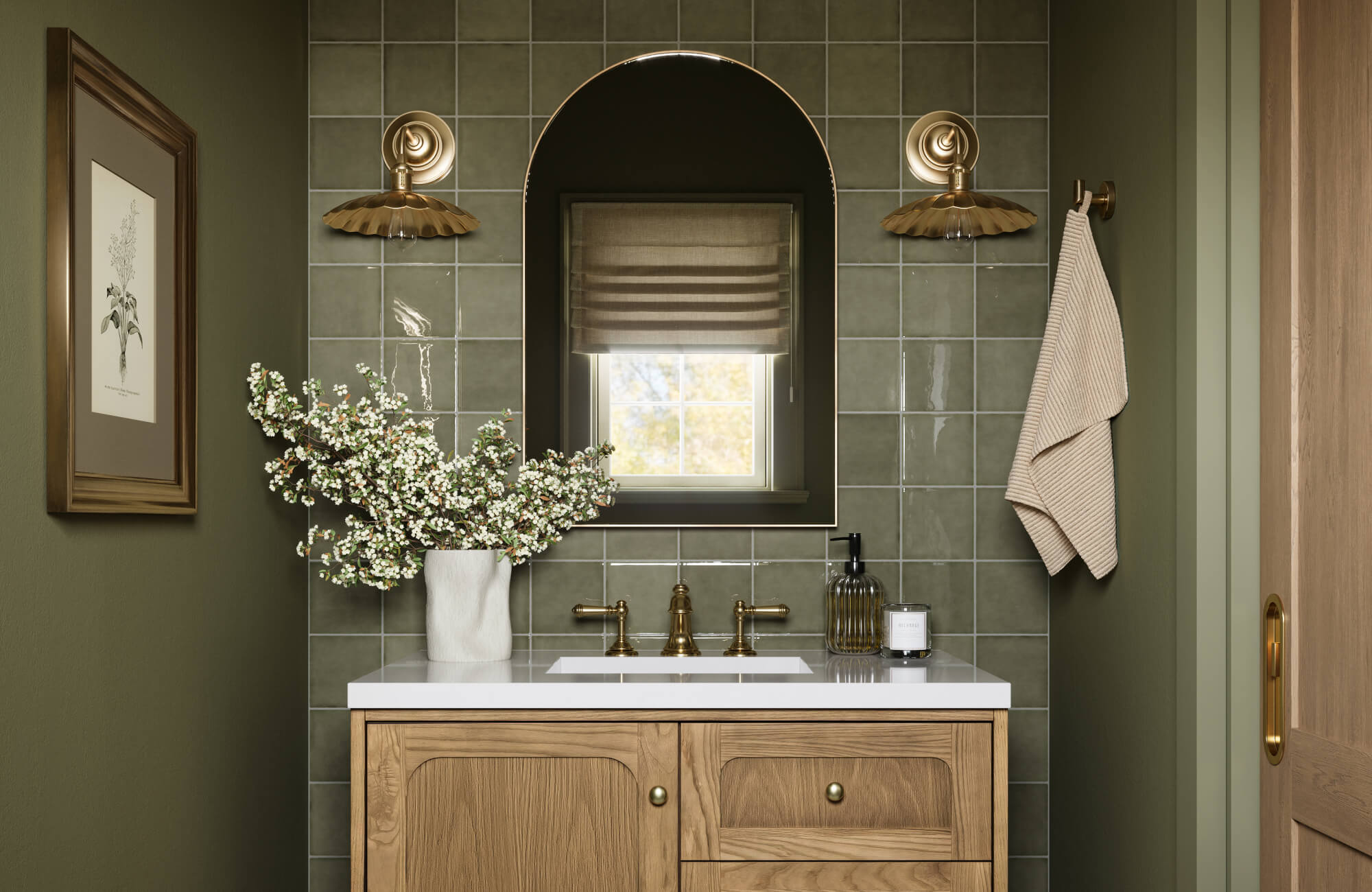 Glossy olive green tiles surround a brass-framed arched mirror, paired with scalloped sconces and a warm wood vanity.