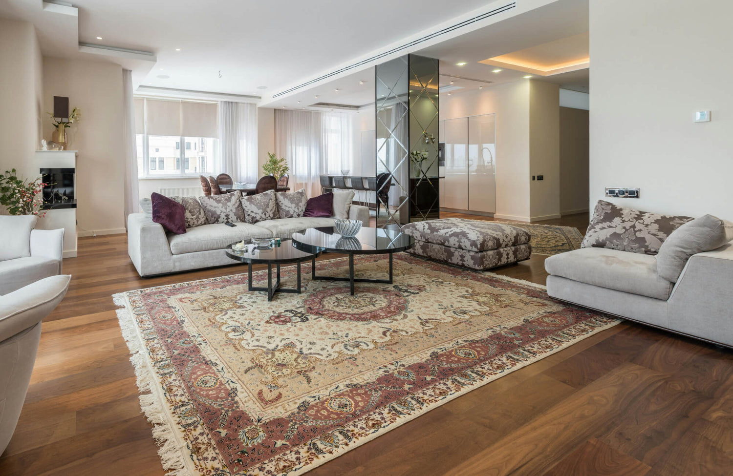 Traditional living room featuring a Persian-style area rug, neutral modern sofas, and warm wood flooring for timeless classic interior elegance