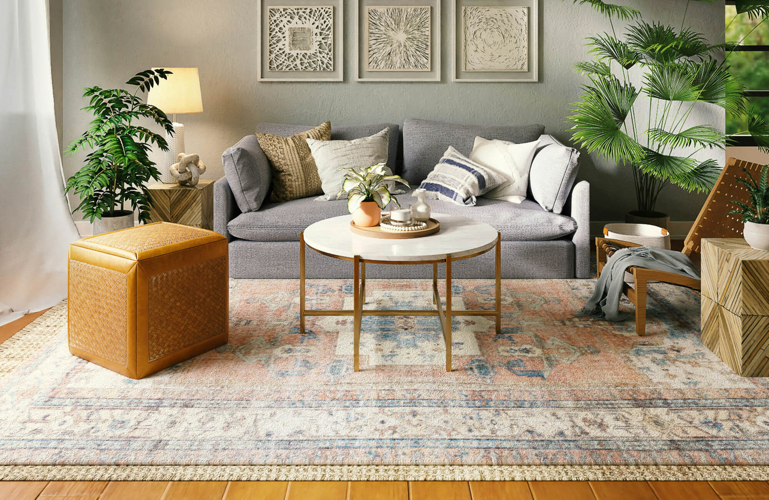 Cozy living room with light wood-look plank flooring, a patterned area rug, gray sofa, layered textiles, and lush greenery.