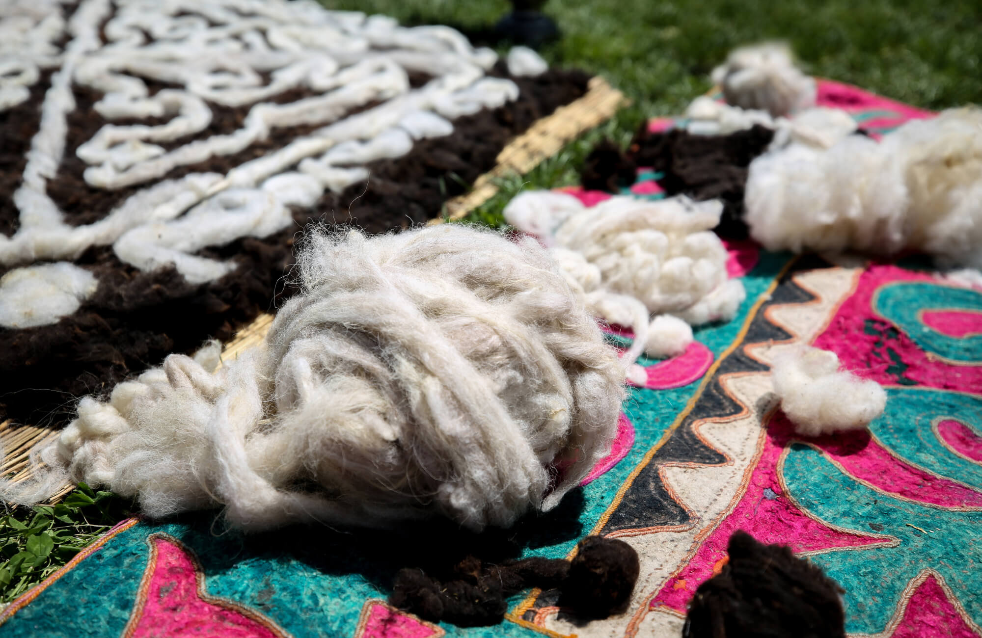 Raw wool fibers laid on a patterned rug during the early stages of rug making, highlighting natural texture and material preparation.
