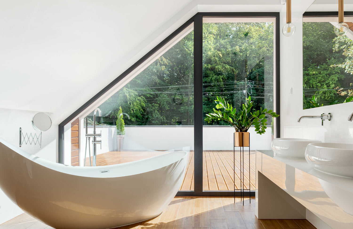 Modern bathroom with freestanding bathtub, double sink vanity, and large slanted glass window overlooking a green outdoor view.