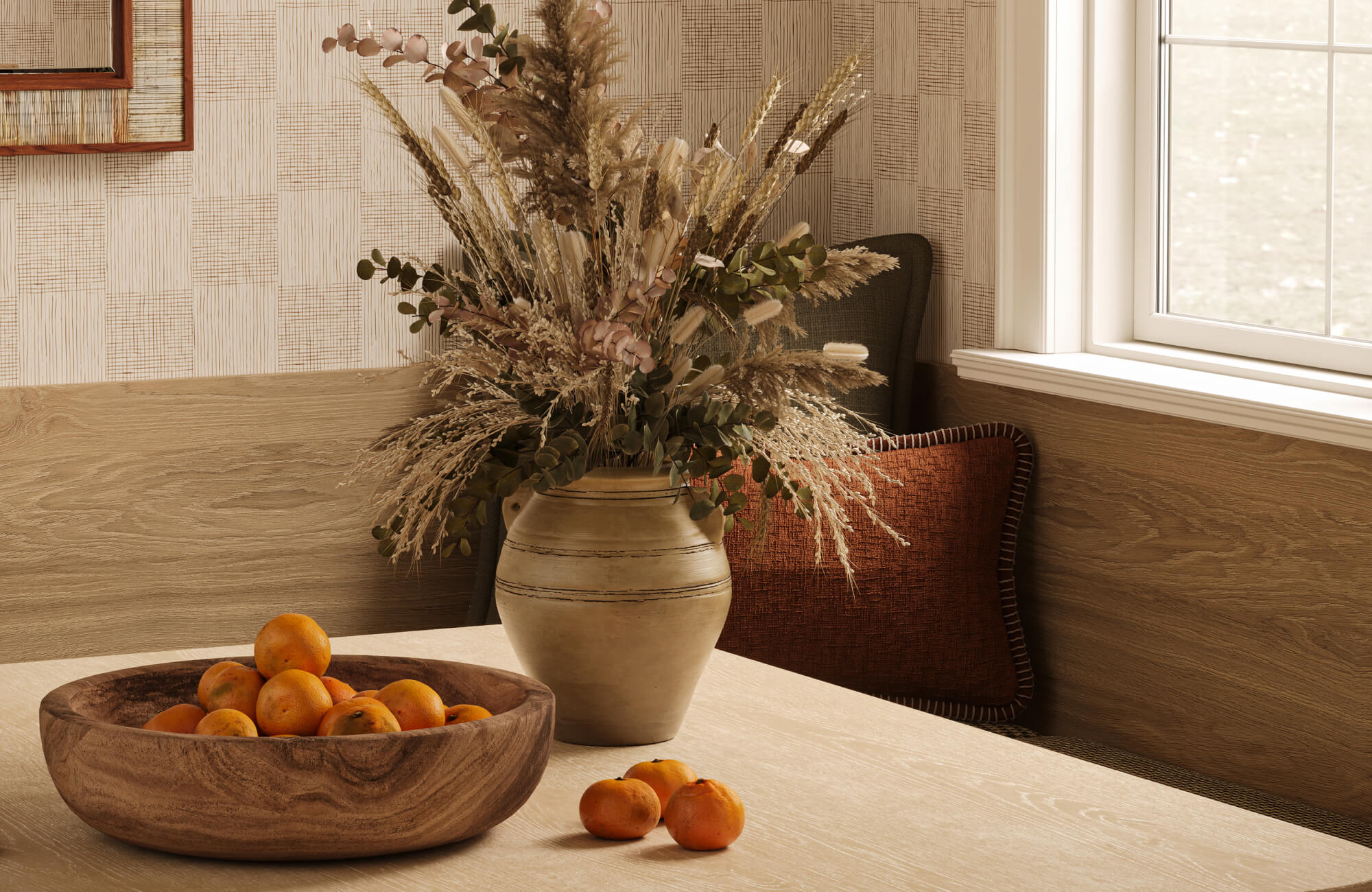 Placed at the center of a light wood table, a decorative bowl filled with oranges adds an organic focal point among layered natural textures and earthy tones.