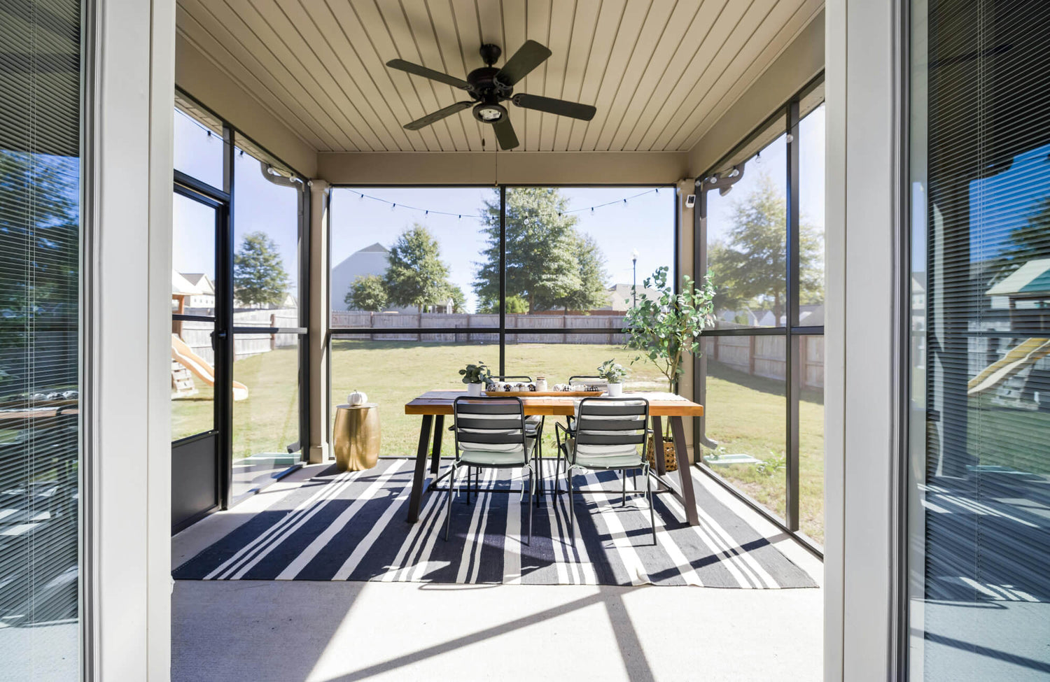 Striped flatweave outdoor rug under dining table in a screened patio, adding style and function to the space.