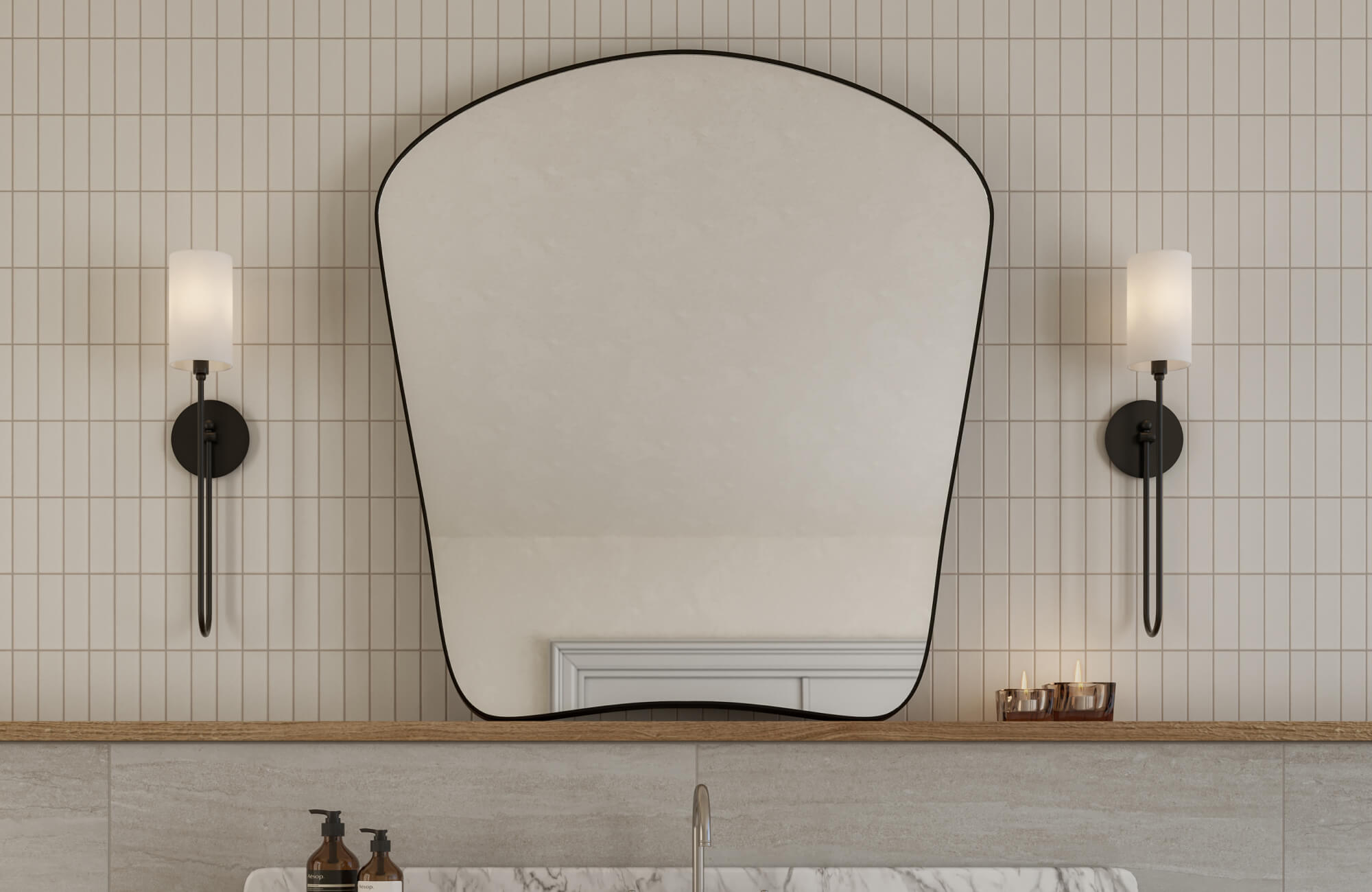 Arched mirror with a slim black frame, flanked by modern wall sconces, set against vertical, straight lay cream tiles in a chic bathroom.