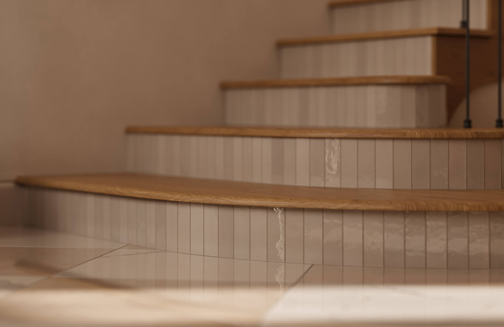 Close-up of staircase risers clad in glossy cream subway tile with vertical stacked layout, paired with natural oak stair treads in a warm contemporary interior.