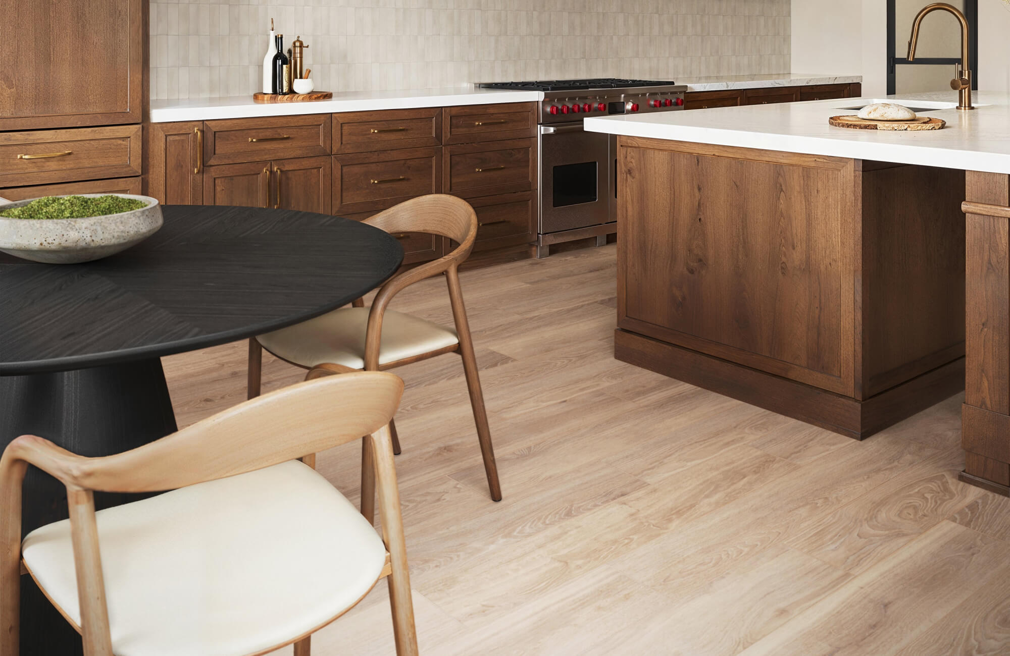 Kitchen with light wood-look tile flooring beneath warm wood cabinetry and a modern dining area.