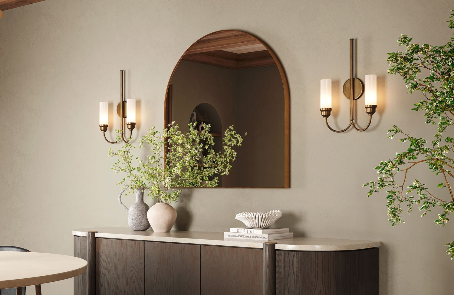 Stylish console setup featuring an arched mirror, twin wall sconces, and decorative vases with fresh branches for a balanced, modern look.