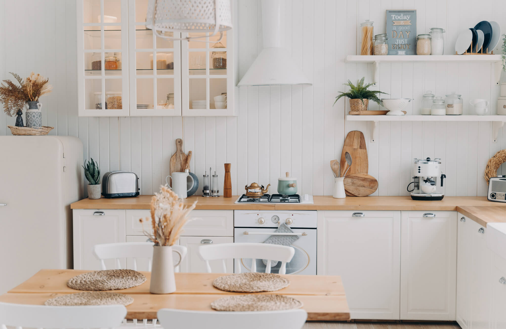 Bright, airy kitchen with white cabinetry, wood countertops, and open shelving, styled with neutral decor and natural light.