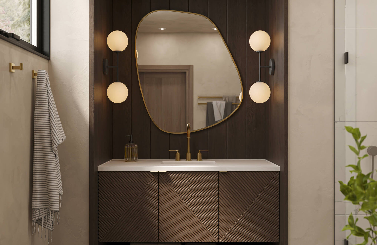Modern bathroom vanity with a dark wood cabinet, white countertop, and brass faucet, styled with an organic-shaped mirror and warm globe sconces on paneled walls.