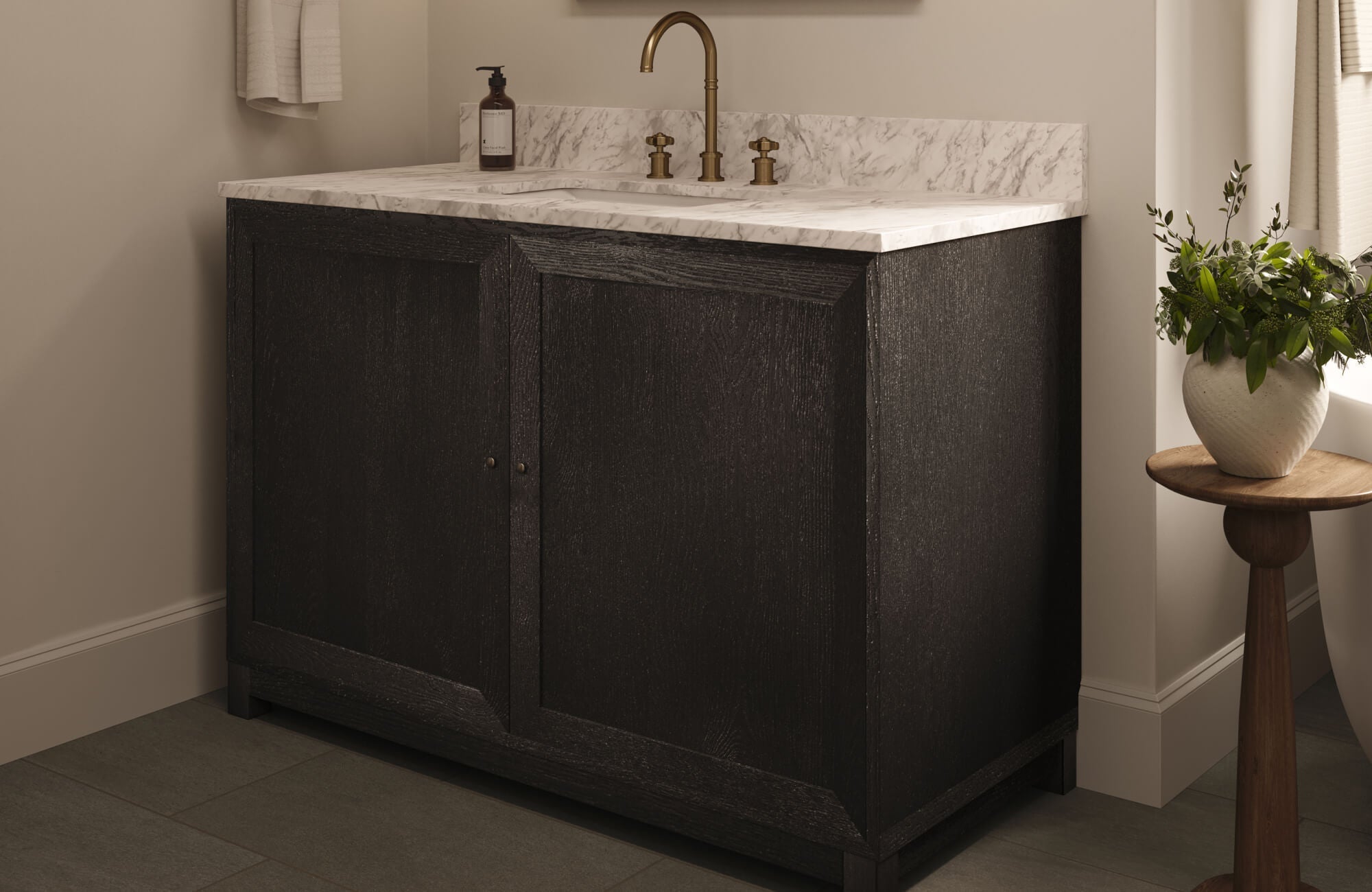 Elegant bathroom with a black wood vanity, marble countertop, and brass fixtures, set atop cement look floor tiles.