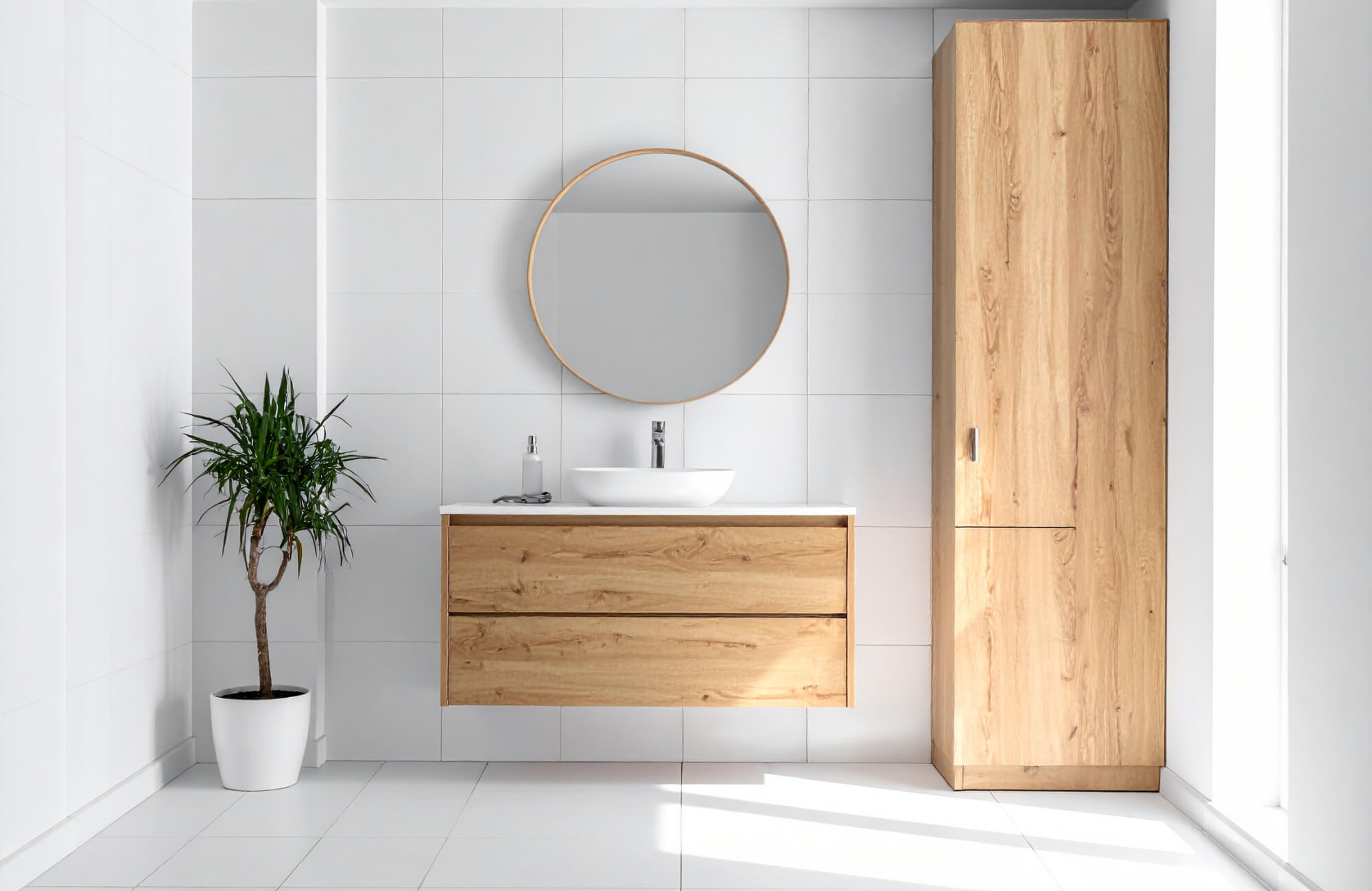 Modern bathroom with a light oak floating vanity, tall oak cabinet, round mirror, and white tile walls.