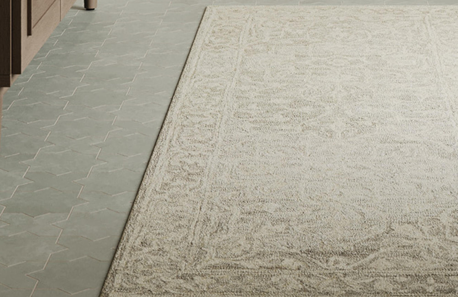 Close-up view of a neutral-toned wool area rug showcasing a soft, textured surface with subtle patterning, placed alongside geometric tile flooring for a refined, modern contrast.
