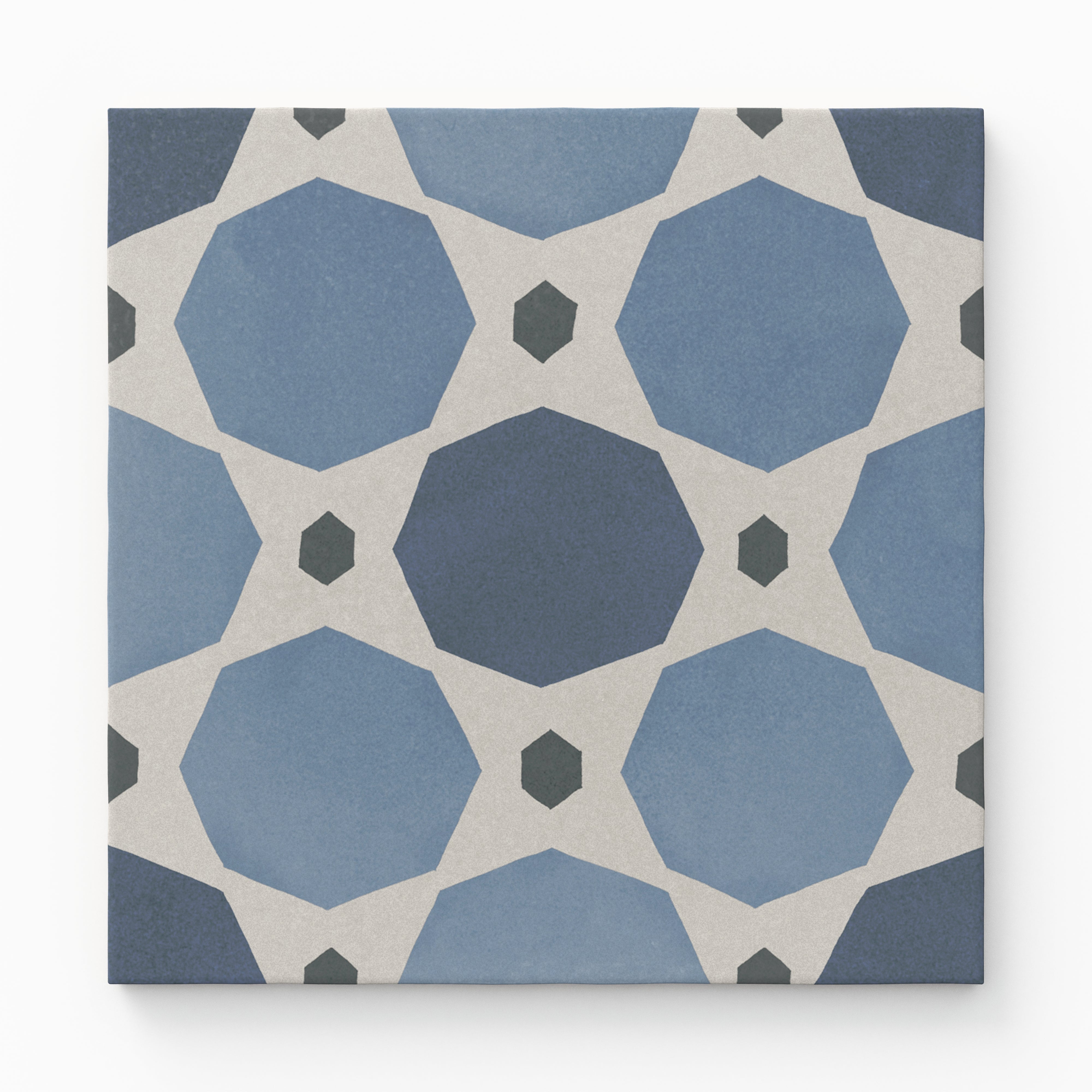 An 8x8 matte porcelain decorative tile with blue-toned interlocking octagonal shapes in gradient navy and sky blue, connected by off-white diamonds and small charcoal hexagons.