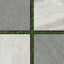 Stone-look outdoor porcelain tiles in neutral tones are arranged in a a checkerboard layout over grass, showcasing anti-slip, textured surfaces ideal for modern patios or garden paths