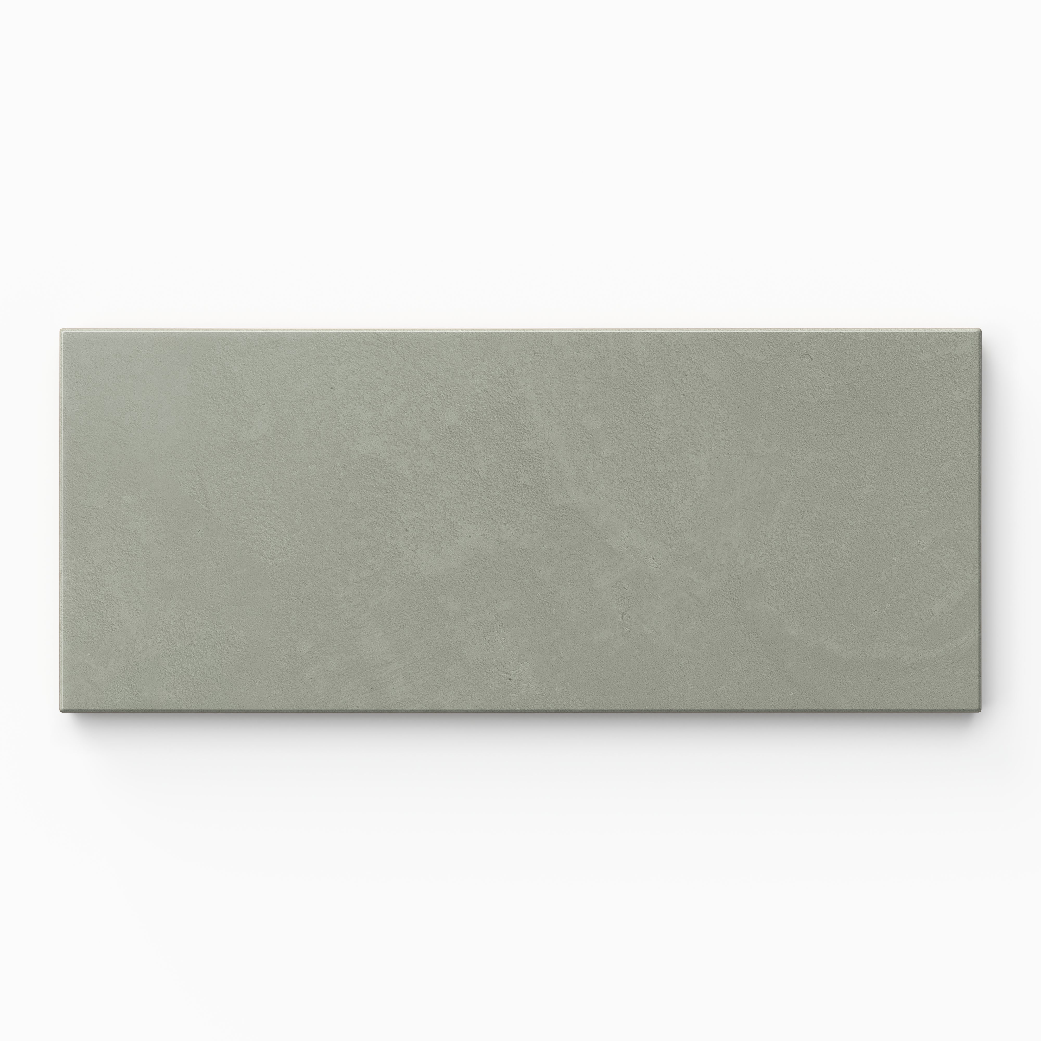 Isabel 2.5x12 Matte Porcelain Tile in Seasalt shows gentle sage green shading across an elongated subway shape, with a quiet cement-plaster surface and a smooth matte finish.
