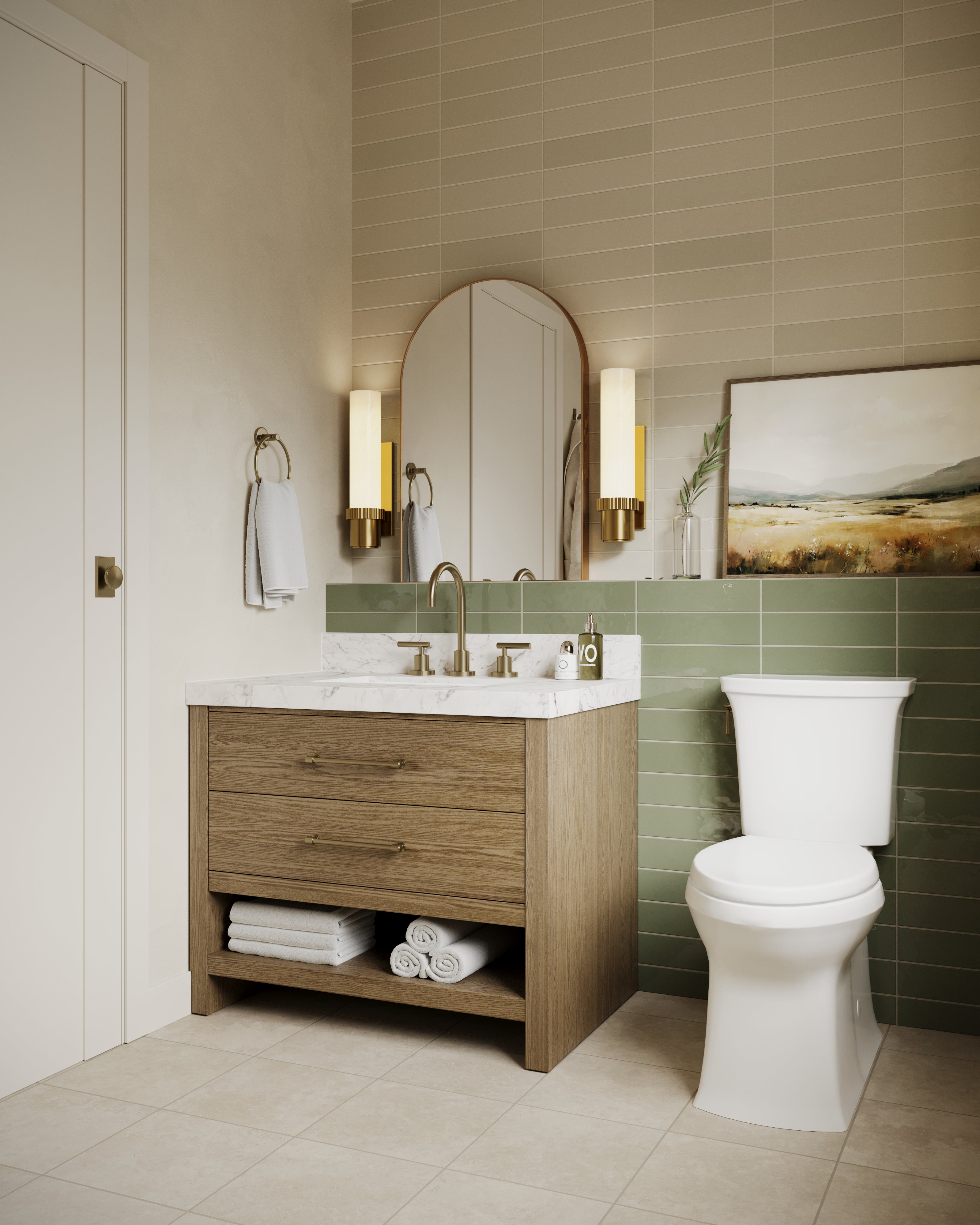Brass bathroom wall sconces with tall cylindrical diffusers and fluted metal bases framing an arched mirror above the vanity, creating warm ambient lighting against beige and green tiles in a modern bathroom.