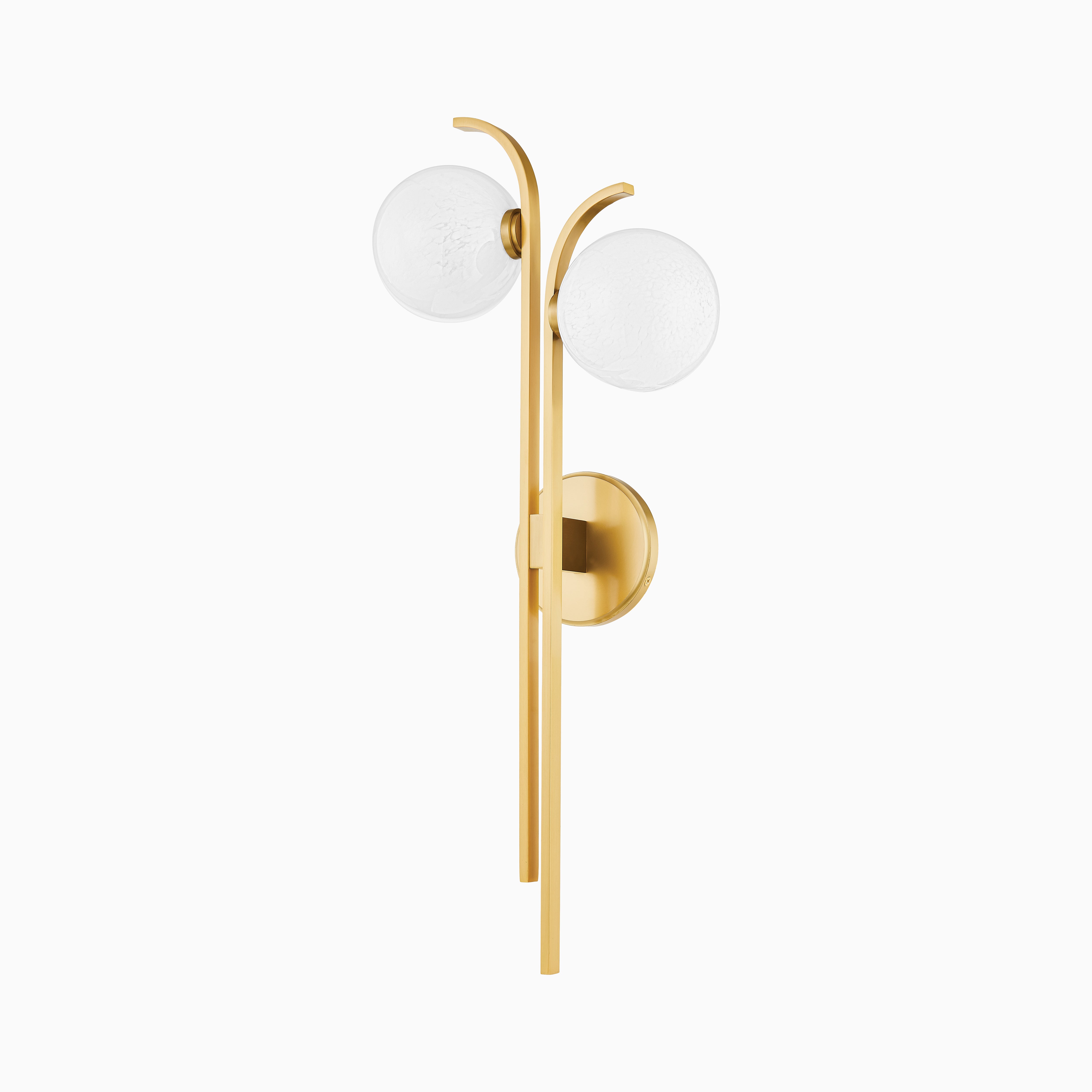Wall sconce in aged brass with two curved arms holding textured glass globes, mounted on a round brass base in a modern design.