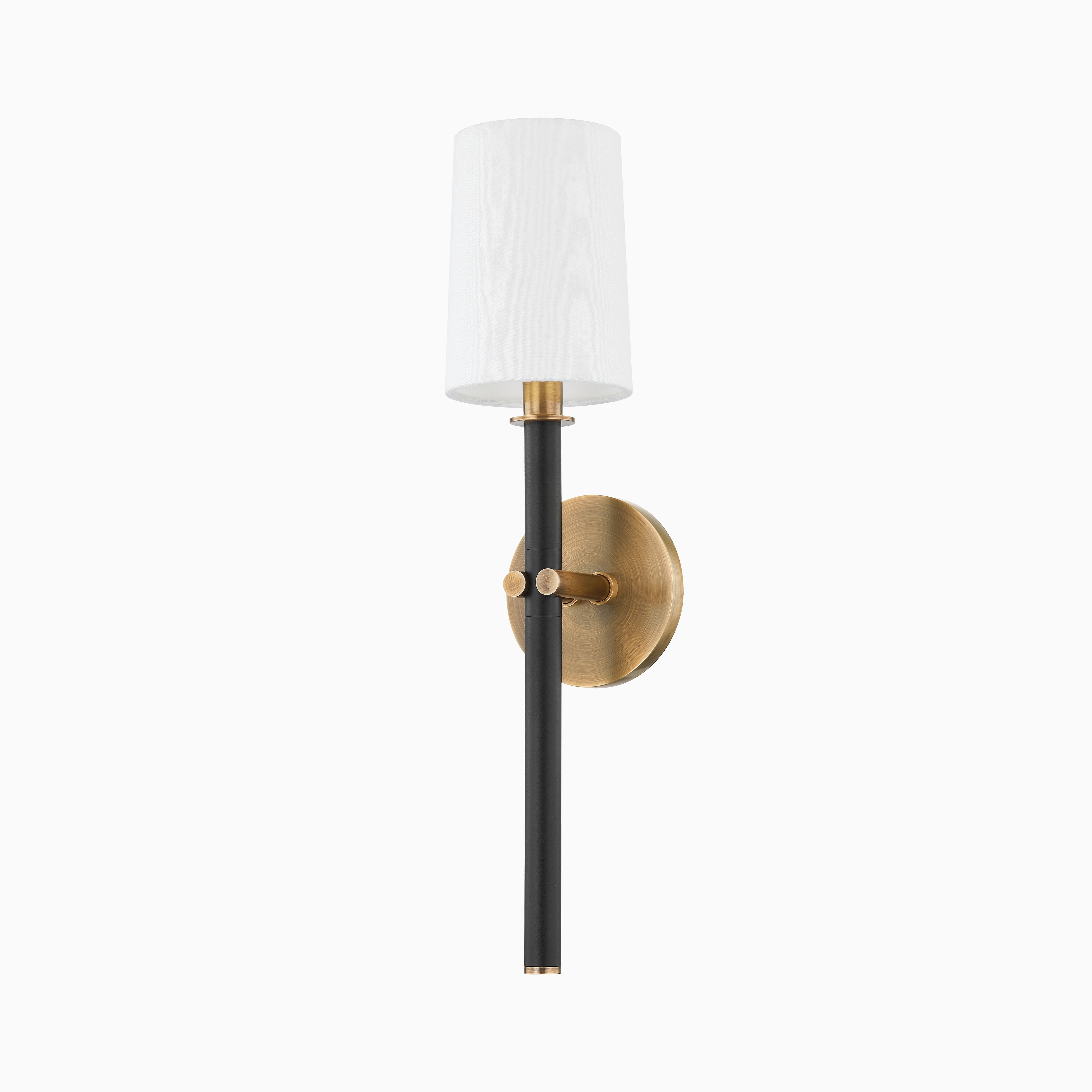 Patina brass wall sconce with round backplate, black metal stem, and white cylindrical shade for a sleek, modern contrast design.