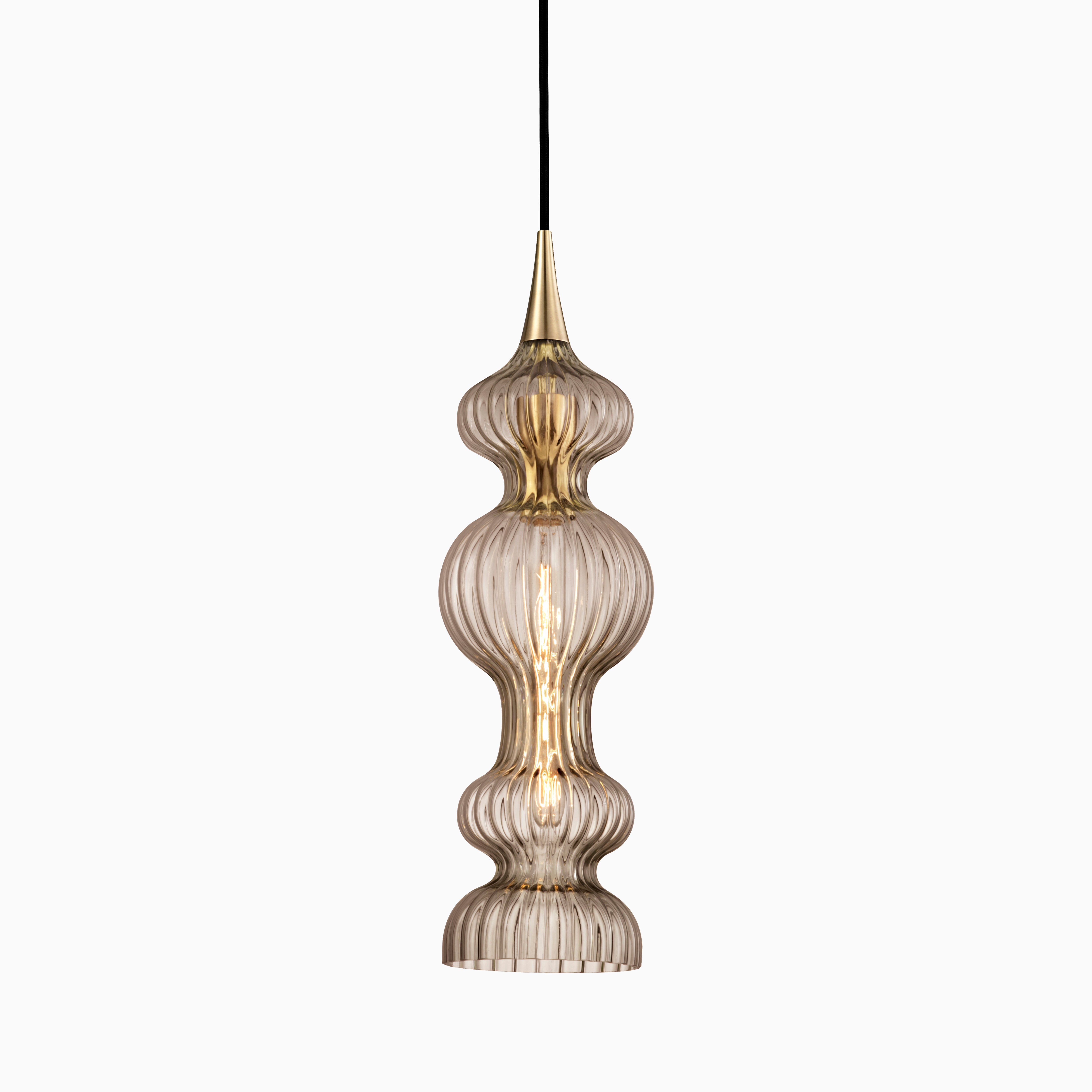 Elongated pendant with ribbed bronze glass and aged brass accents, radiating warm, shimmering light through sculptural curves.