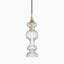 Elongated pendant with tiered, ribbed glass and aged brass accents, casting shimmering light through sculptural curves.