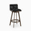 Swivel counter stool with tufted black leather seat, low backrest, and bronze angular base featuring a circular footrest.