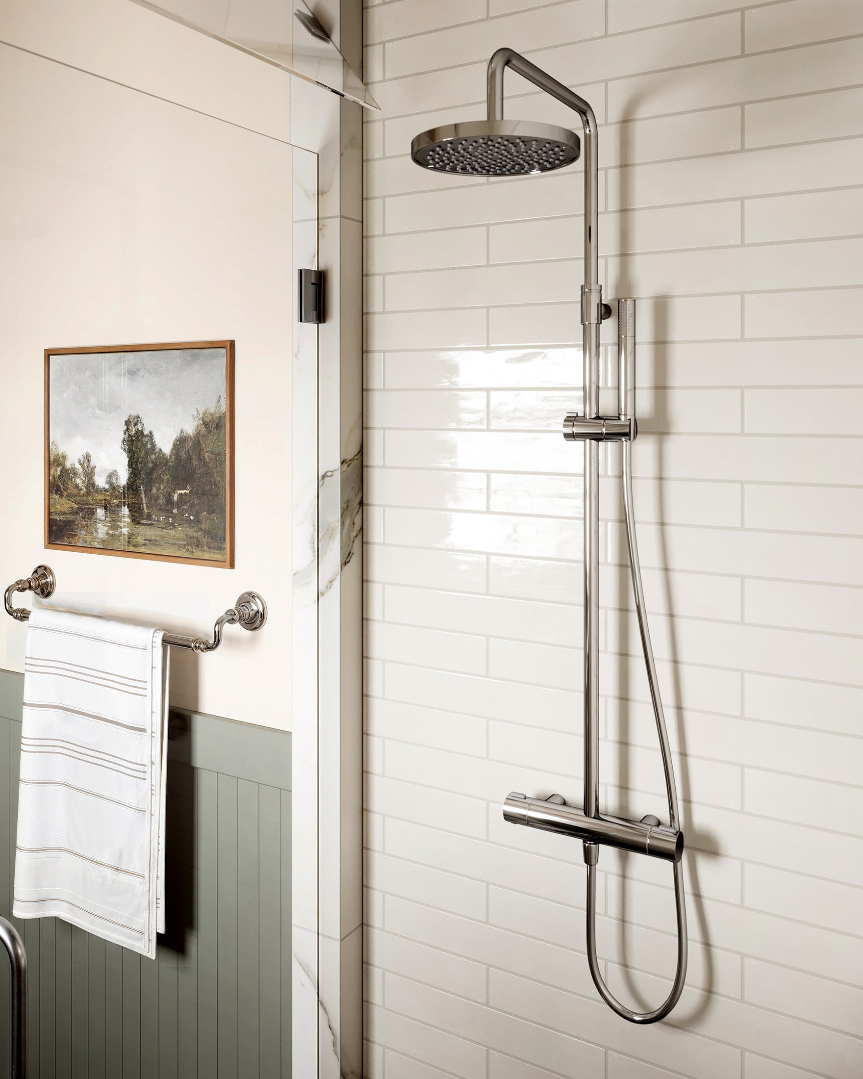 Glossy off-white subway tiles in a shower space with sleek chrome fixtures and a modern rainfall showerhead.